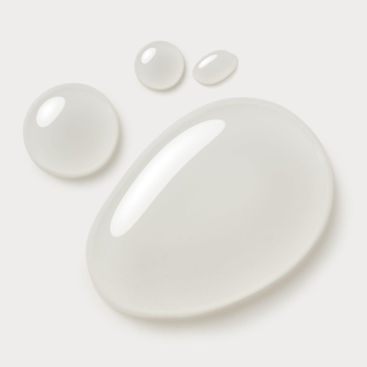 Drops of clear cleansing oil on a pale background