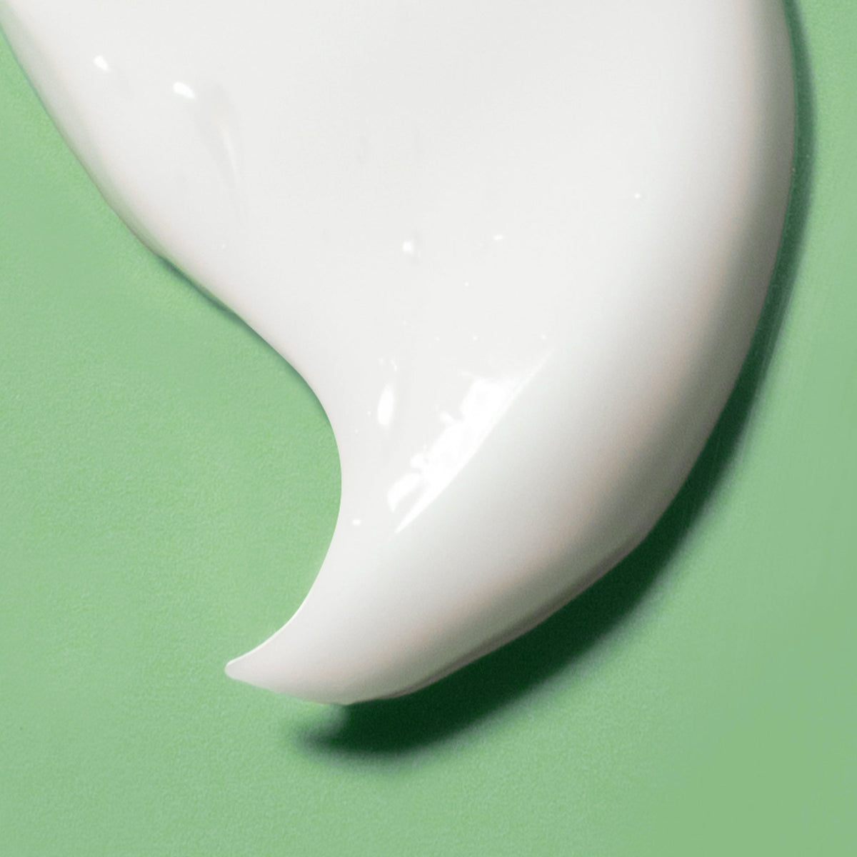 A swipe of white centella cream on a green background