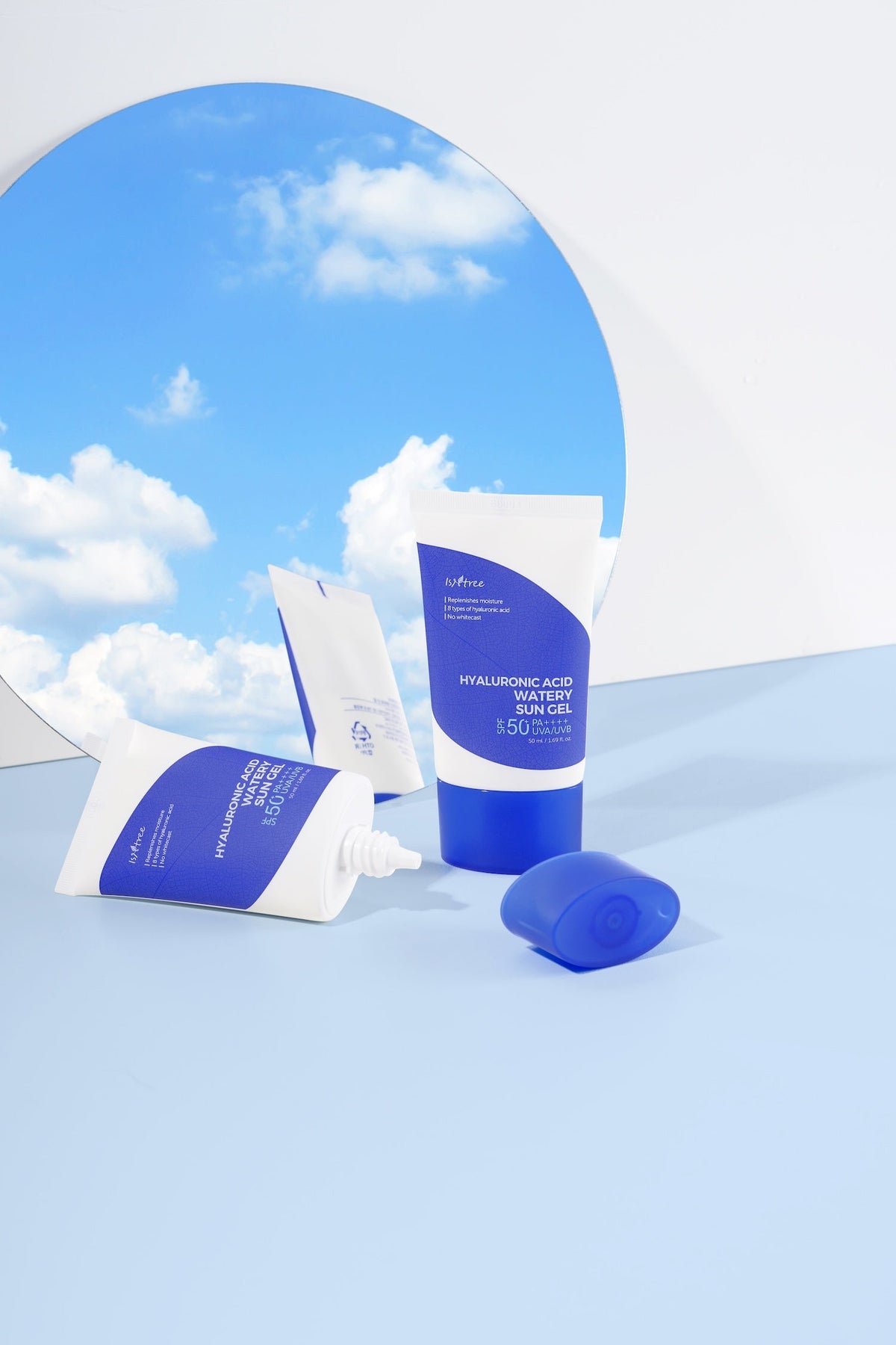 Tubes of watery sun gel in front of a mirror reflecting blue sky